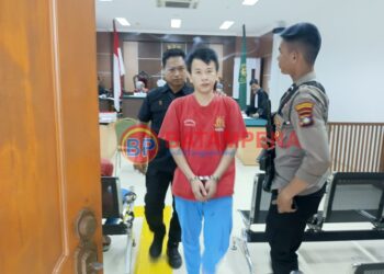 Terdakwa Selamat alias Ferry alias Along digiring oleh pengawal tahanan dari Kejari Batam, Rizal. (Sumber foto: JP - BatamPena.com)