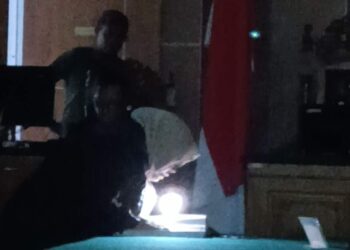 JPU Siti baca visum et repertum dengan cara menyalakan lampu senter dari ponselnya. (Sumber foto: JP - BatamPena.com)