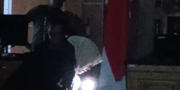 JPU Siti baca visum et repertum dengan cara menyalakan lampu senter dari ponselnya. (Sumber foto: JP - BatamPena.com)