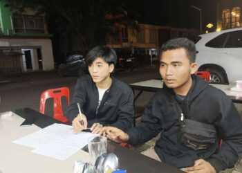 Regi Setiawan sedang memegang pena untuk menandatangani surat perjanjian damai dengan Joes Aldiansyah Butarbutar. (Sumber foto: JP - BatamPena.com)